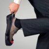 personne en train d'enfiler une sur-chaussure antiglisse par dessus sa chaussure de ville marron