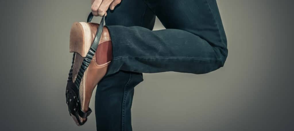 personne en train d'enfiler une sur-chaussure antiglisse par dessus sa chaussure de ville marron
