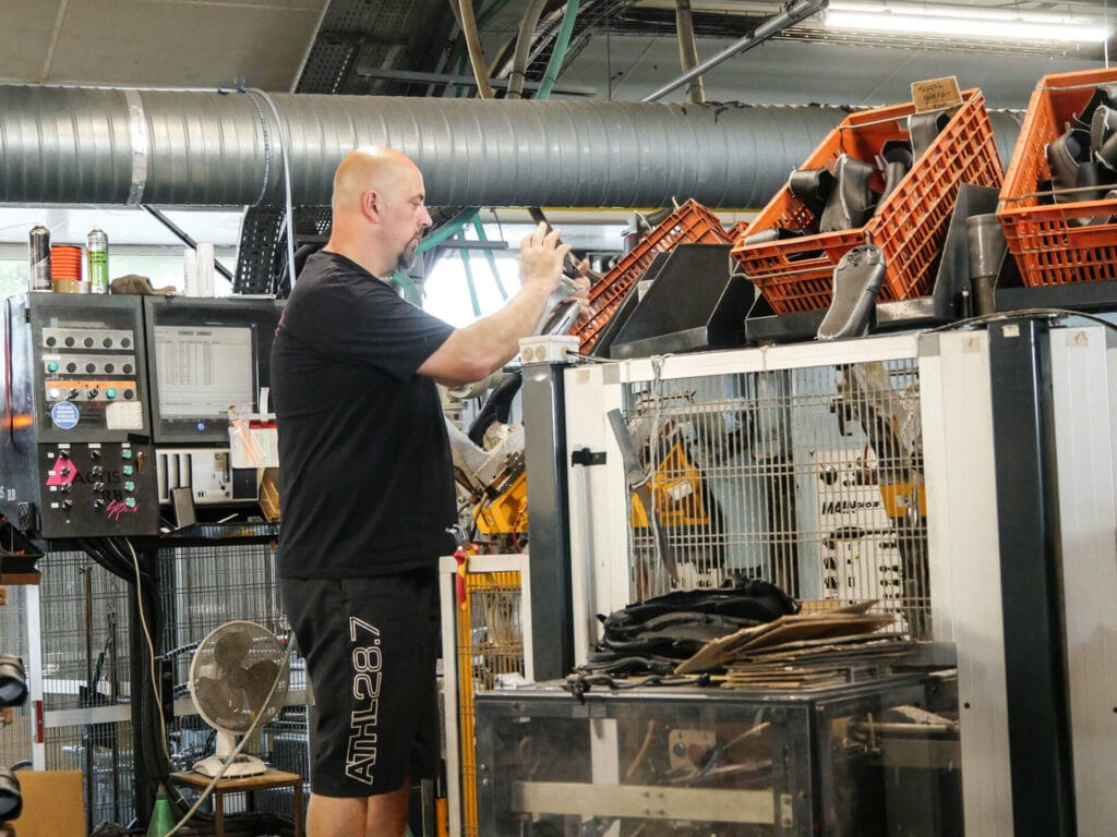 homme debout habillé en noir travaillant sur une machine dans un atelier