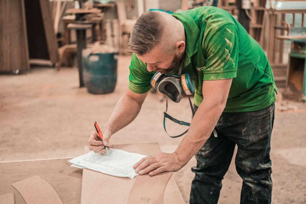un homme en t-shirt vert en train d'écrire sur un papier dans un atelier