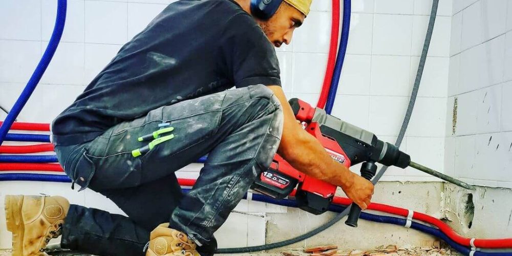 homme à genoux tenant une grosse perceuse