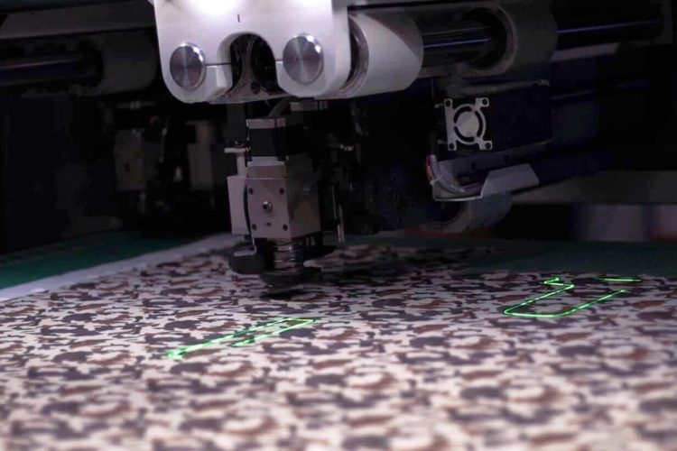 machine à découpe couteau en train de découper un textile au motif camouflage