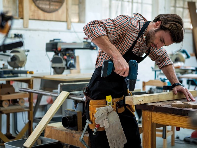 homme avec une perceuse dans un atelier de menuiserie