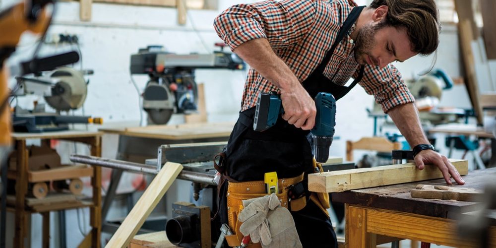 homme avec une perceuse dans un atelier de menuiserie