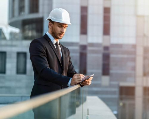 homme en costume avec un casque en train de prendre des notes au milieu des building