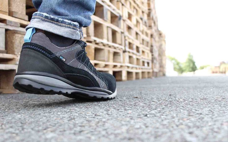 arrière d'une chaussure de sécurité noire devant des palettes en bois