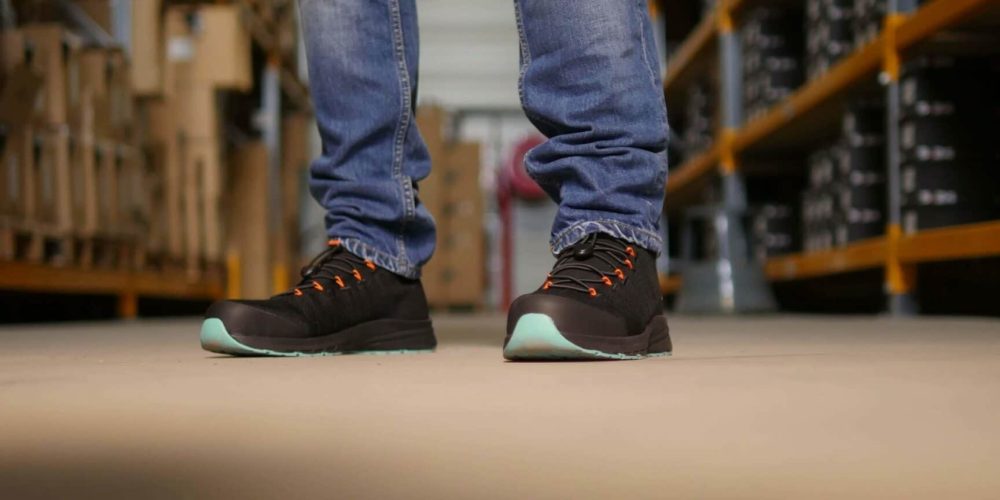 personne dans un entrepôt qui porte des baskets de sécurité noires