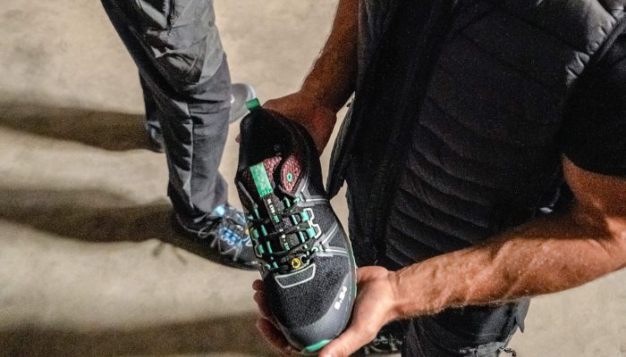 homme habillé en noir tenant une chaussure dans les mains