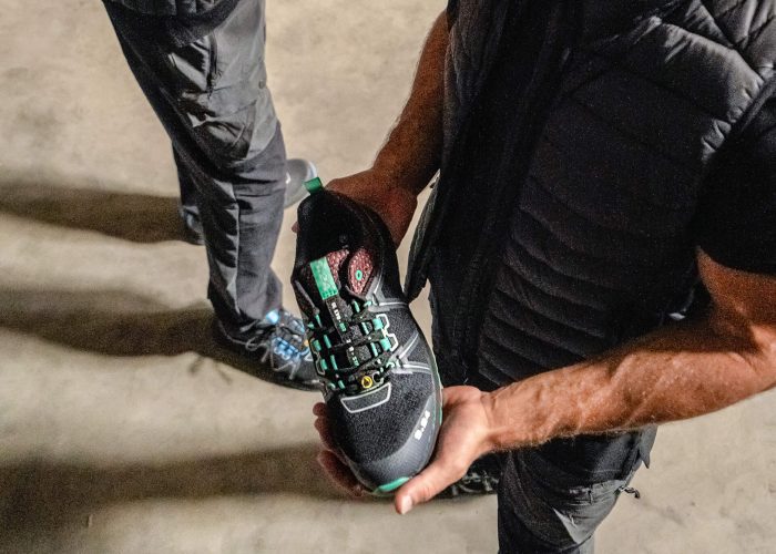 homme habillé en noir tenant une chaussure dans les mains