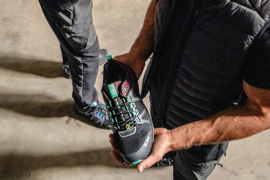 homme habillé en noir tenant une chaussure dans les mains