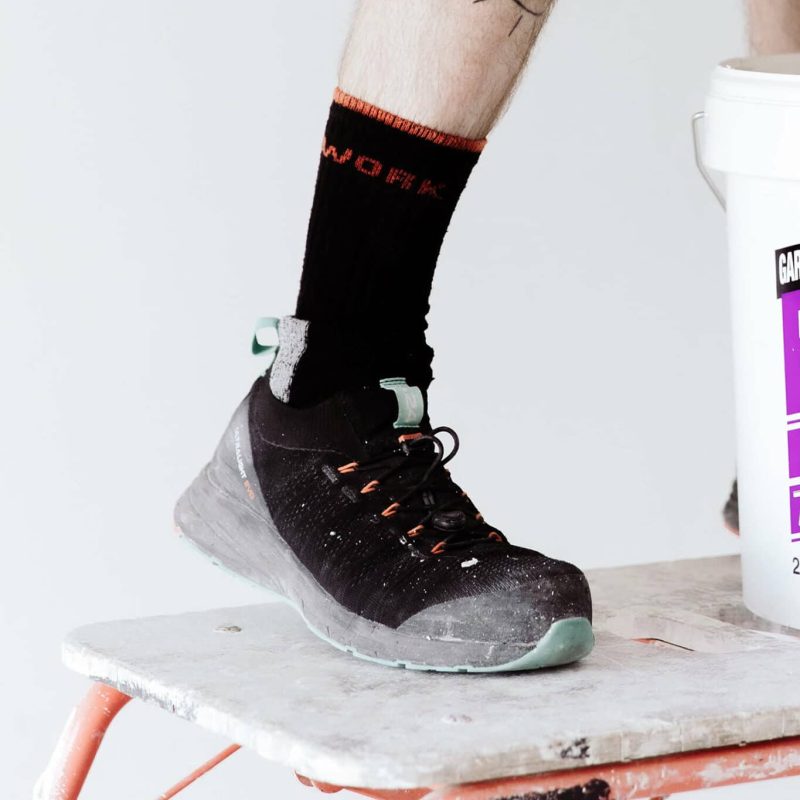 jambe d'un homme en short portant une basket de sécurité noire