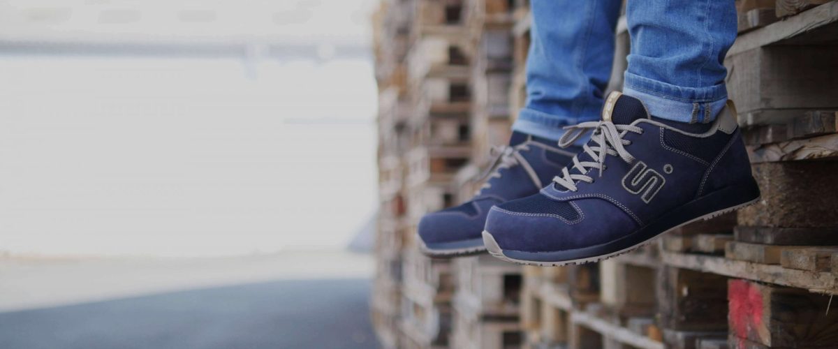 SAMOA S3 pose2 personne assise sur des palettes bois portant des chaussures de sécurité bleu marine