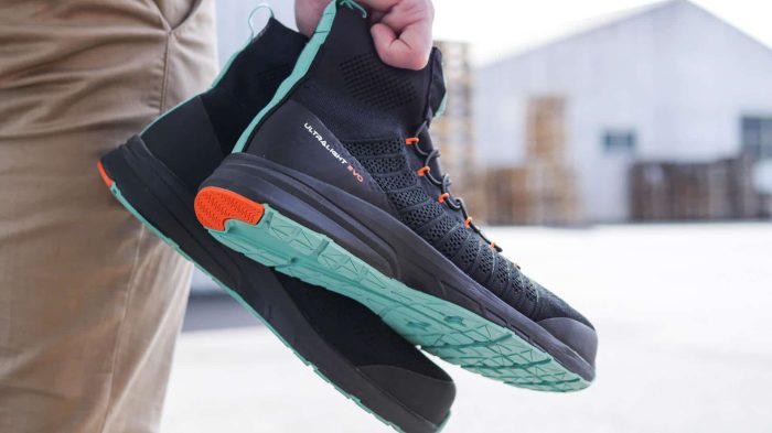 main qui tient une paire de baskets de sécurité noires montantes