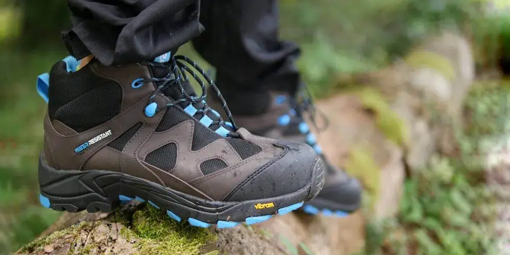 chaussures de sécurité montantes marron, noir et bleu type randonnée dans la forêt