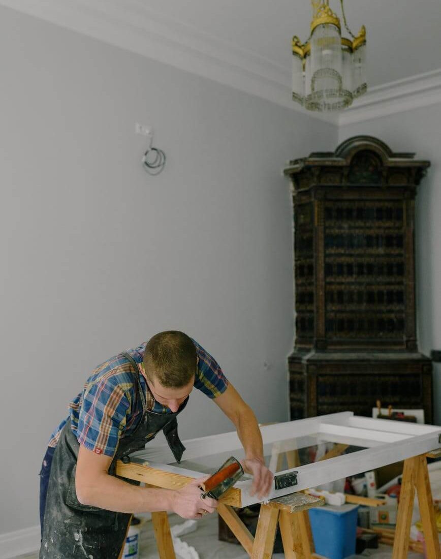 un artisan debout dans un appartement, en train de travailler sur une menuiserie
