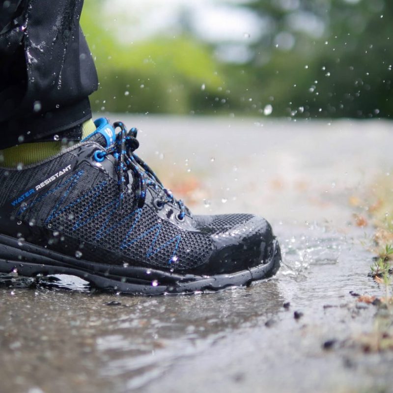 Chaussure de sécurité noire basse homme et femme S3 WR HRO polyvalente, en extérieur marchant dans une flaque d'eau