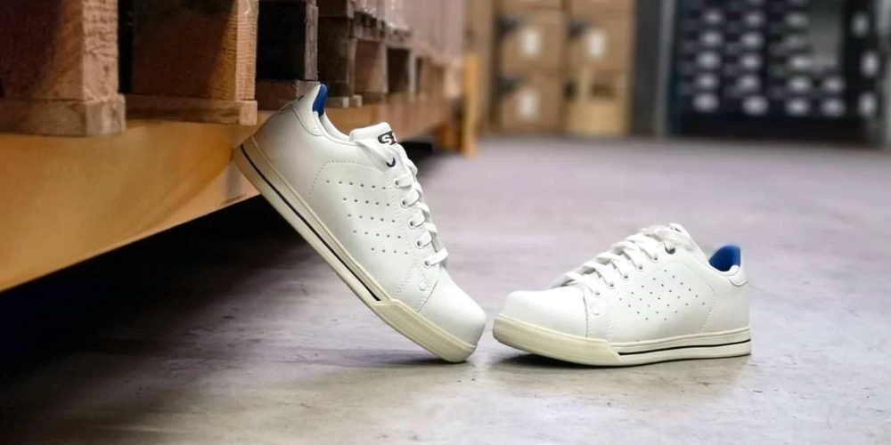 paire de baskets de sécurité blanches au sol dans un entrepôt