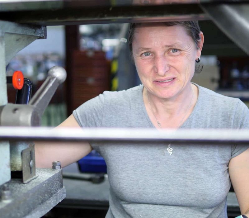 femme souriante en t-shirt gris qui travaille dans un atelier