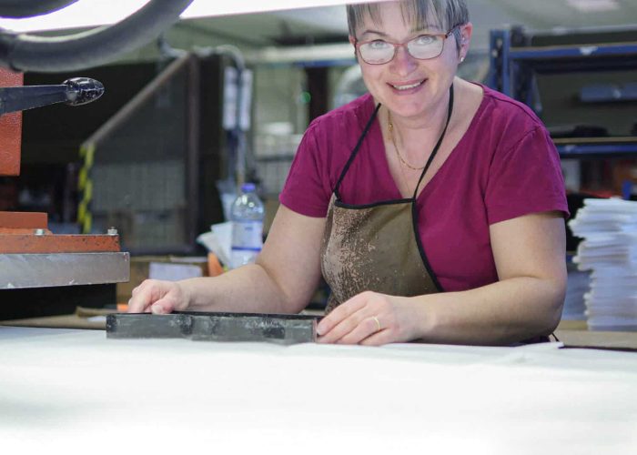 femme souriante, habillée en rose en train de travailler sur une machine dans un atelier