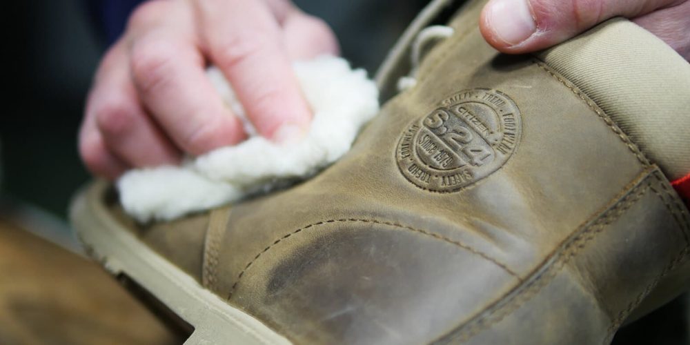 personne qui fait l'entretien d'une chaussure en cuir marron