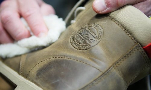 personne qui fait l'entretien d'une chaussure en cuir marron