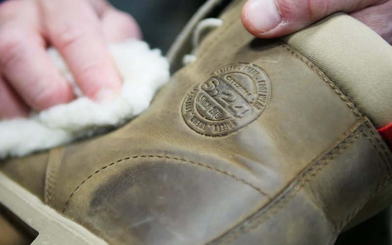 personne qui fait l'entretien d'une chaussure en cuir marron