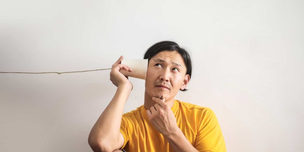 homme en t-shirt jaune pensif qui écoute dans un gobelet