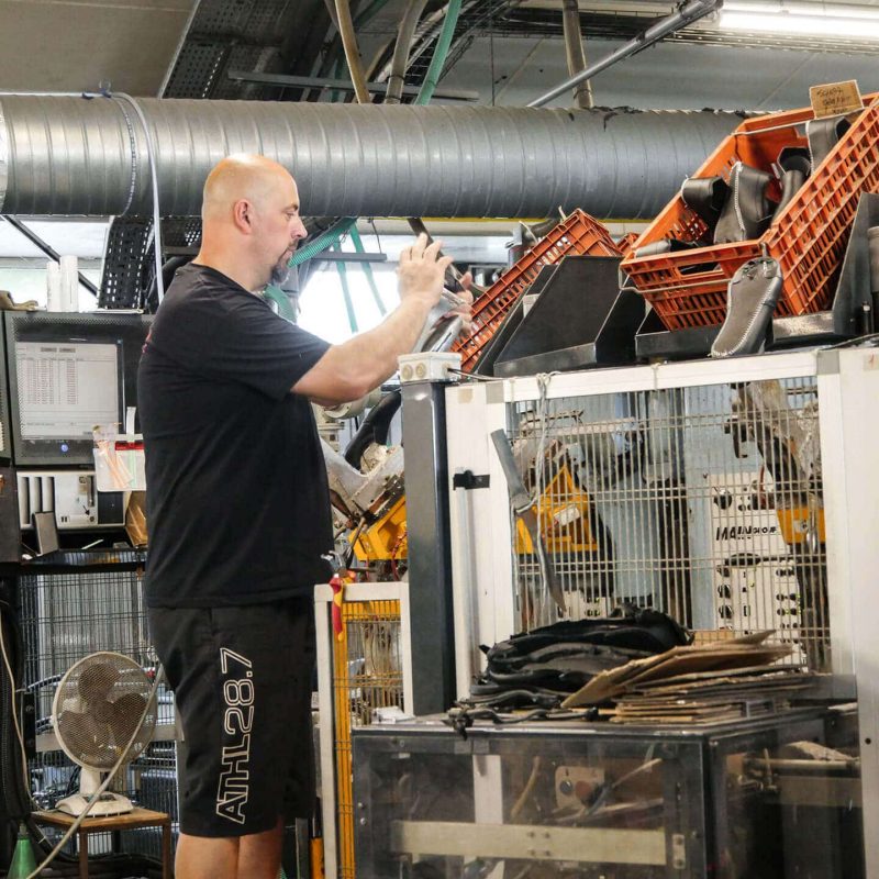 homme debout habillé en noir travaillant sur une machine dans un atelier