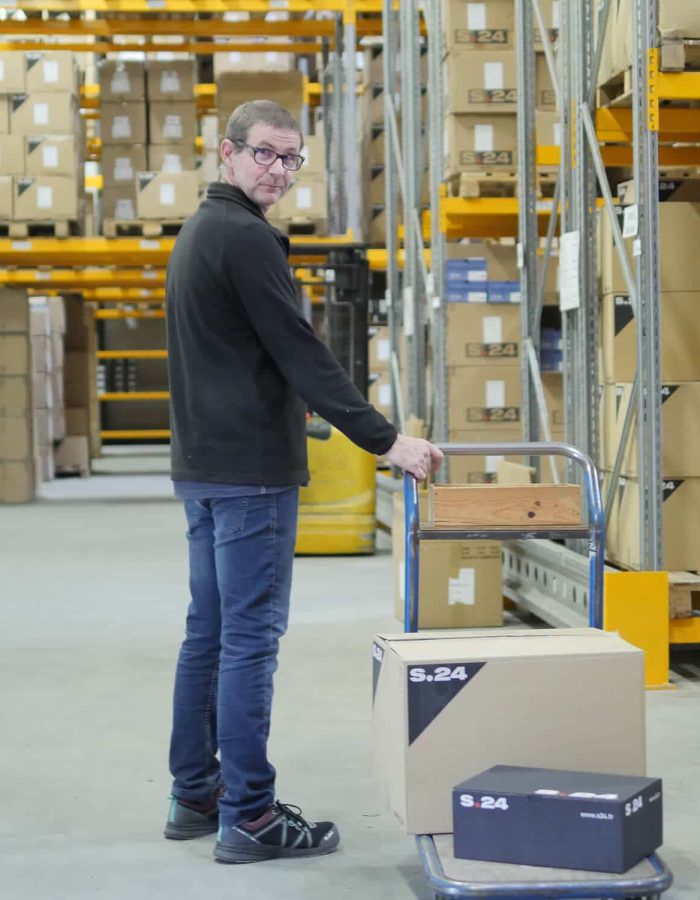 homme debout dans un entrepôt tirant un charriot