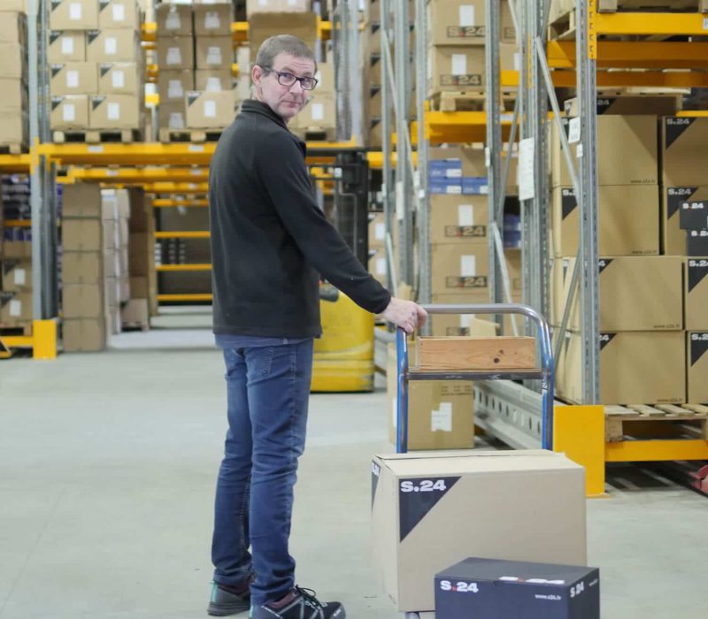 homme debout dans un entrepôt tirant un charriot