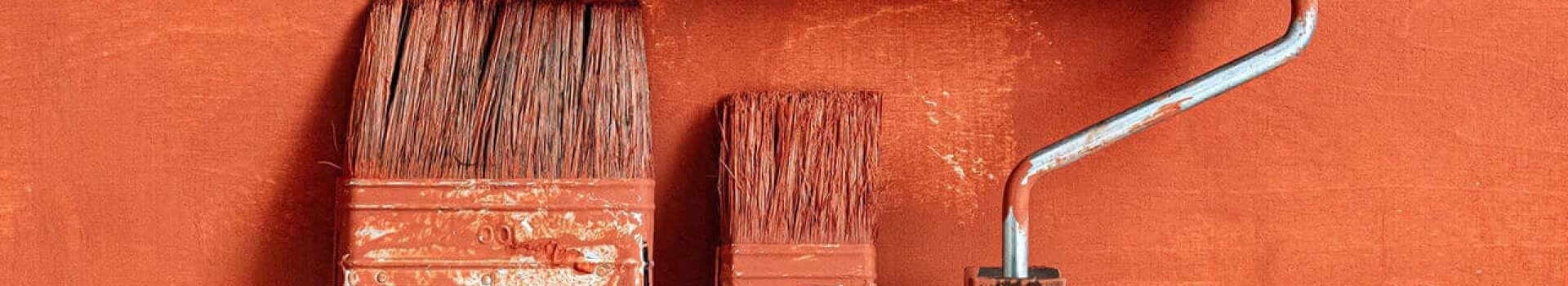 peinture orange mur carré pinceaux et rouleau de peinture appuyés sur un mur orange