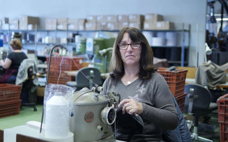 femme avec des lunettes qui travaille sur une machine à coudre dans un atelier