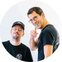 deux hommes souriants habillés en noir avec un pinceau