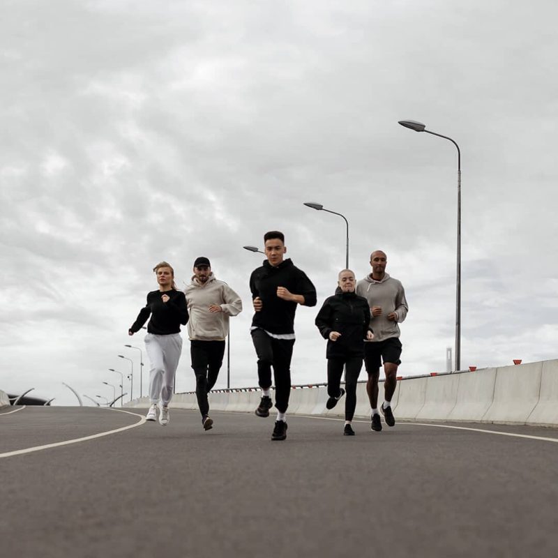 groupe d'hommes et de femmes en train de courir sur une route