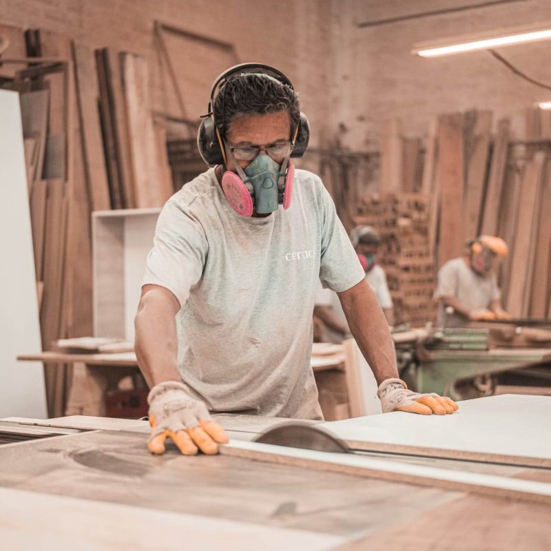 un homme avec un masque et un casque dans un atelier de menuiserie