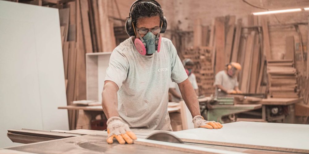 un homme avec un masque et un casque dans un atelier de menuiserie